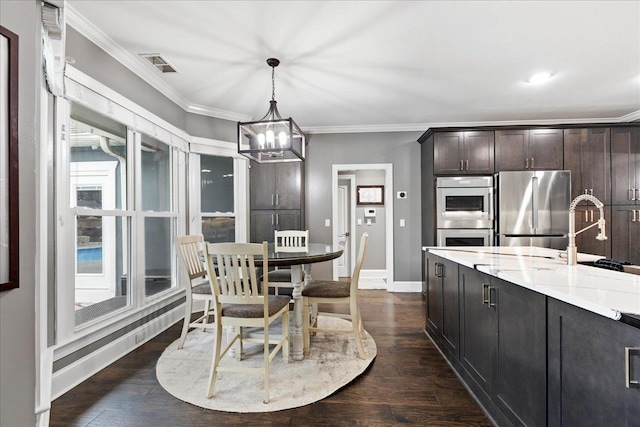 dining space with sink, crown molding, dark hardwood / wood-style floors, and a chandelier