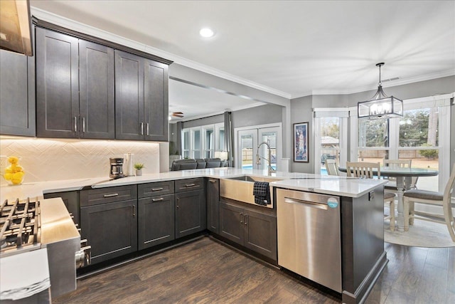 kitchen with sink, dark wood-type flooring, dishwasher, decorative light fixtures, and kitchen peninsula