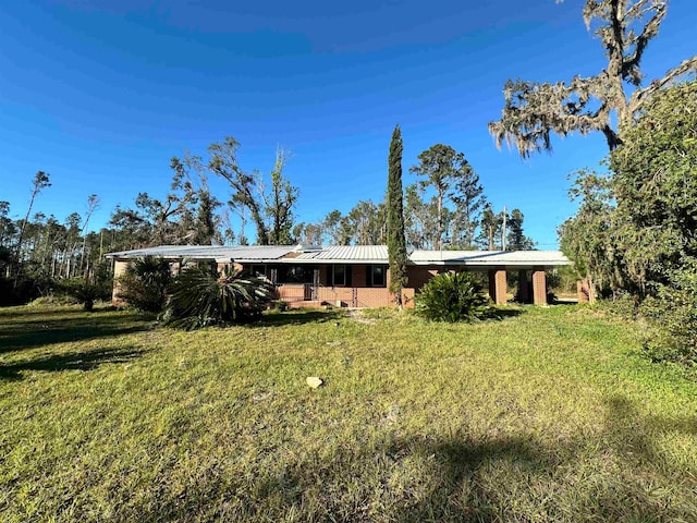 back of property featuring a carport and a lawn