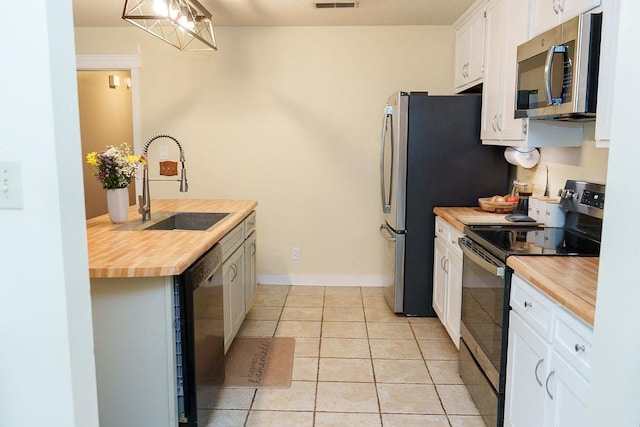 1839 Meriadoc Rd, Tallahassee, FL 32303 - kitchen with appliances with stainless steel finishes, butcher block countertops, light tile patterned floors, and white cabinets