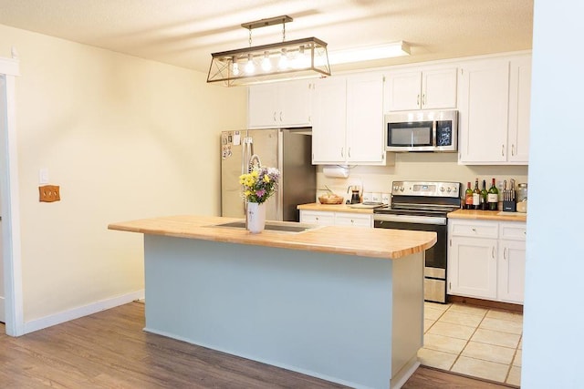 1839 Meriadoc Rd, Tallahassee, FL 32303 - kitchen featuring stainless steel appliances, white cabinets, a kitchen island, light countertops, and light wood-style flooring