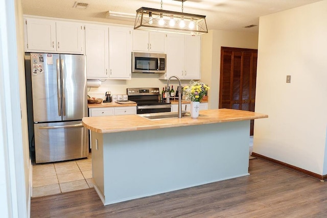 1839 Meriadoc Rd, Tallahassee, FL 32303 - kitchen with appliances with stainless steel finishes, light countertops, a kitchen island with sink, wood finished floors, and white cabinetry