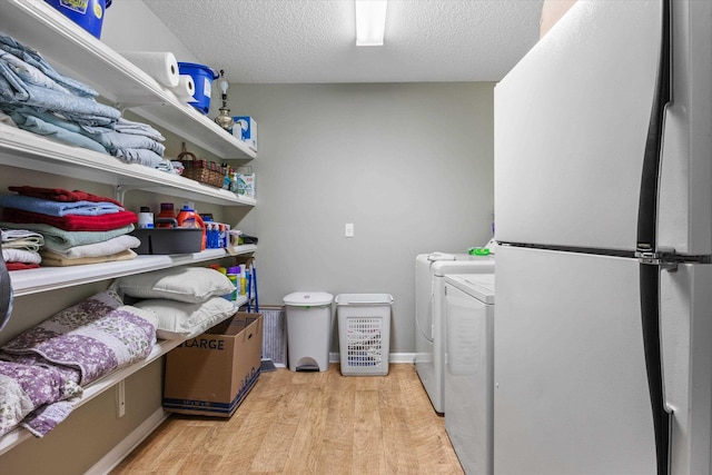 washroom featuring washer and clothes dryer, light hardwood / wood-style flooring, and a textured ceiling