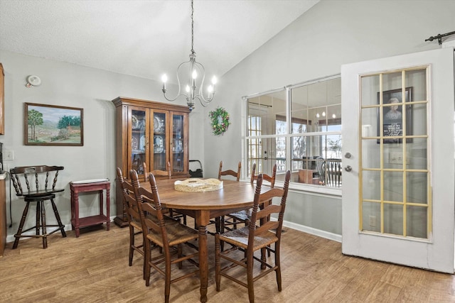 dining space with a notable chandelier, vaulted ceiling, and light hardwood / wood-style floors