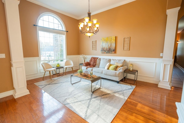 living room with ornamental molding, a notable chandelier, wood-type flooring, and decorative columns