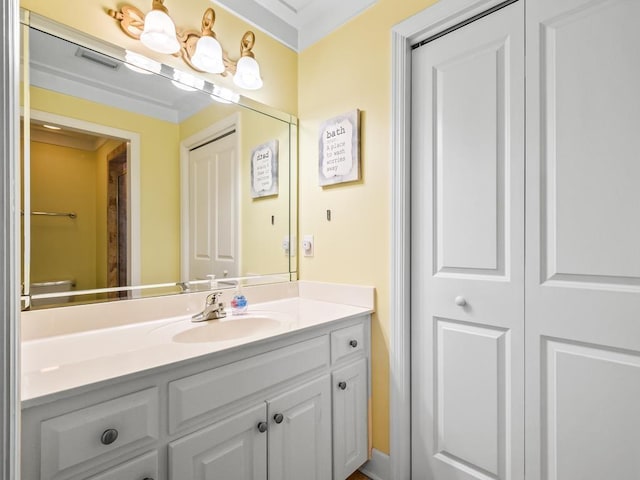 bathroom featuring toilet, vanity, and ornamental molding