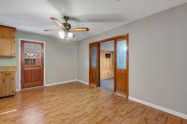 unfurnished dining area with a textured ceiling, light wood-type flooring, and ceiling fan