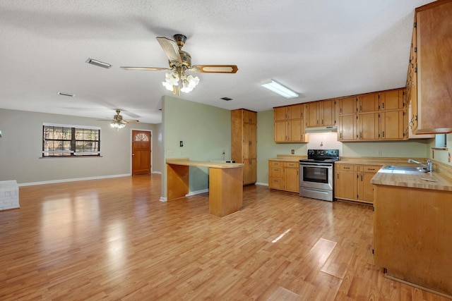 kitchen featuring stainless steel range with electric cooktop, a textured ceiling, sink, and light wood-type flooring