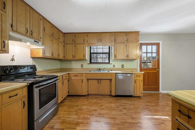 kitchen with appliances with stainless steel finishes, light hardwood / wood-style flooring, a textured ceiling, and sink