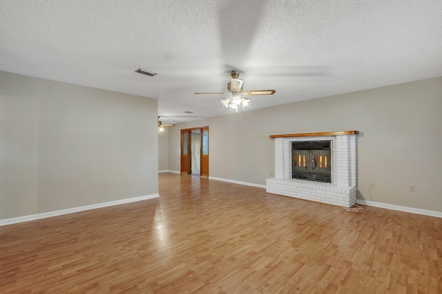 unfurnished living room with a fireplace, a textured ceiling, ceiling fan, and light hardwood / wood-style flooring