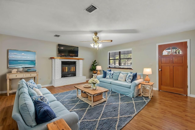 living room with a brick fireplace, ceiling fan, and hardwood / wood-style flooring