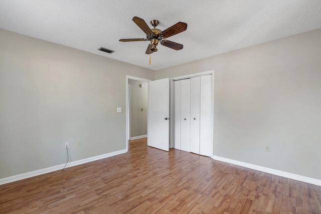 unfurnished bedroom with wood-type flooring, a closet, ceiling fan, and a textured ceiling