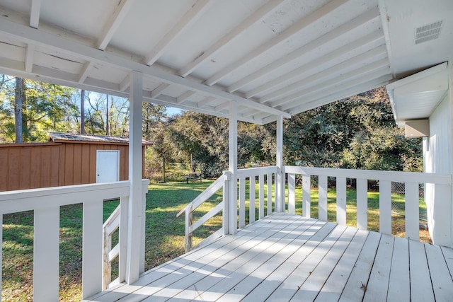 wooden deck featuring a storage unit and a yard