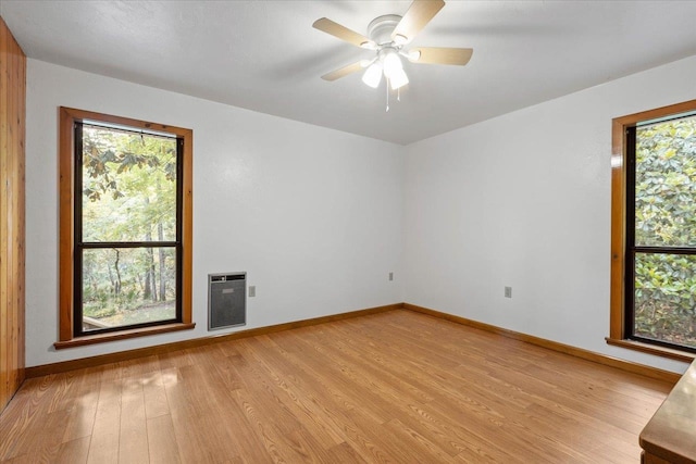 empty room featuring light hardwood / wood-style flooring, ceiling fan, and heating unit