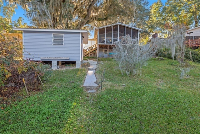 back of property featuring a deck, a lawn, and a sunroom