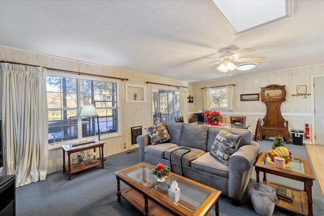 living room with a skylight, plenty of natural light, and ceiling fan