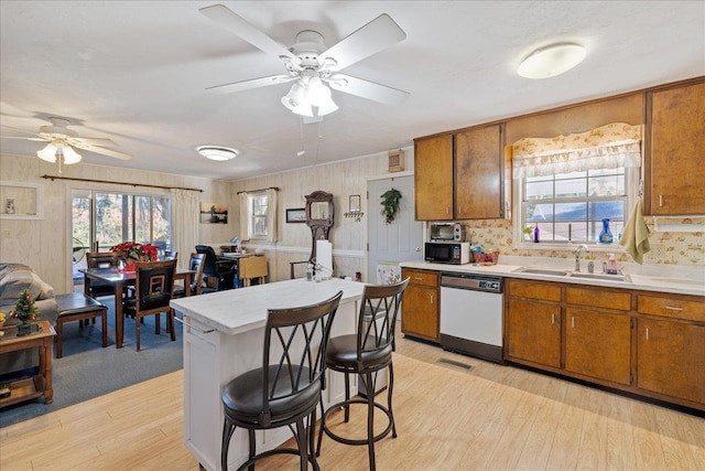 kitchen featuring dishwasher, light hardwood / wood-style flooring, a breakfast bar area, and sink