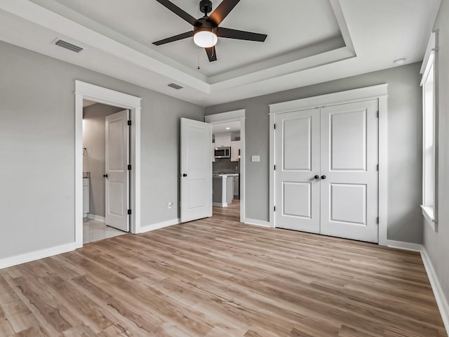1613 Sea Breeze Way, Carrabelle, FL 32322 - unfurnished bedroom with a tray ceiling, visible vents, a closet, and wood finished floors