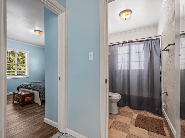 bathroom featuring wood-type flooring, toilet, and ornamental molding