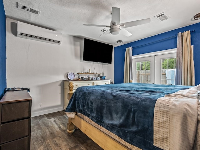 bedroom featuring dark wood-type flooring, french doors, an AC wall unit, ceiling fan, and a textured ceiling