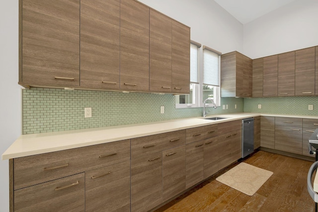 kitchen featuring stainless steel dishwasher, dark wood-type flooring, sink, and tasteful backsplash