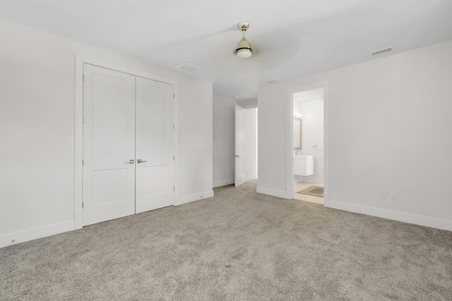 unfurnished bedroom featuring connected bathroom, a closet, ceiling fan, and light colored carpet