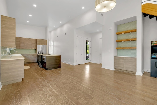 kitchen featuring a high ceiling, a center island, tasteful backsplash, and sink