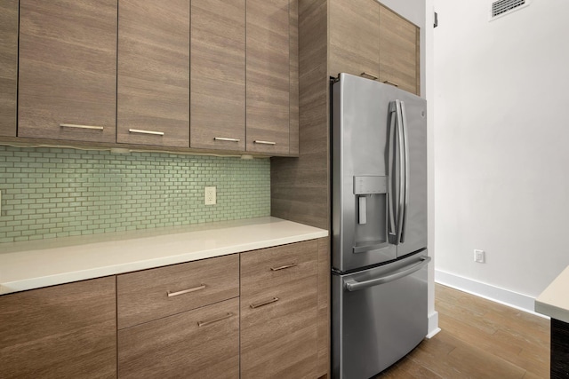 kitchen featuring stainless steel fridge with ice dispenser, backsplash, and hardwood / wood-style flooring