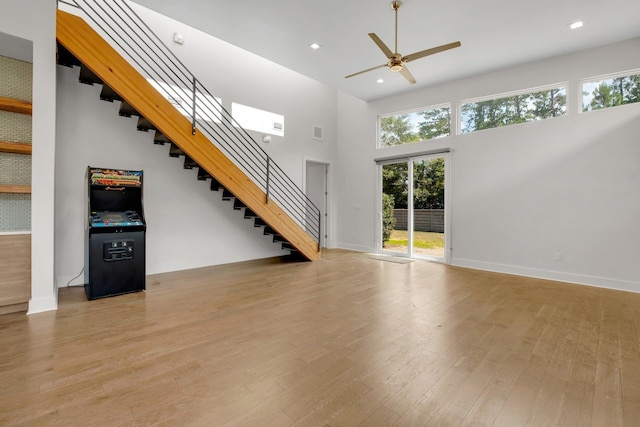 unfurnished living room featuring a high ceiling, light hardwood / wood-style flooring, and ceiling fan