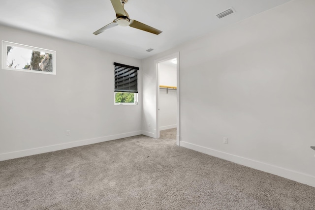 empty room featuring light colored carpet, ceiling fan, and a healthy amount of sunlight