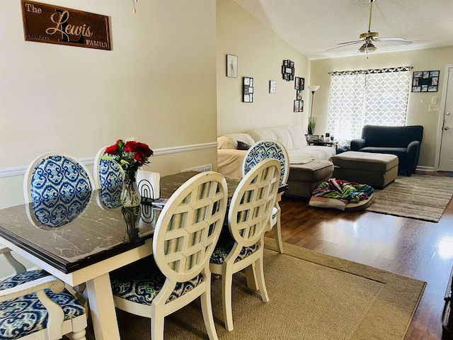 dining space featuring a textured ceiling, dark wood-type flooring, ceiling fan, and vaulted ceiling