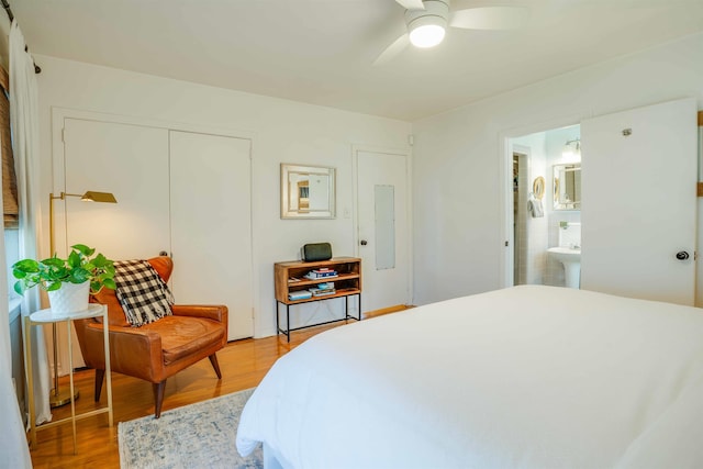 bedroom featuring ceiling fan, connected bathroom, wood-type flooring, and electric panel