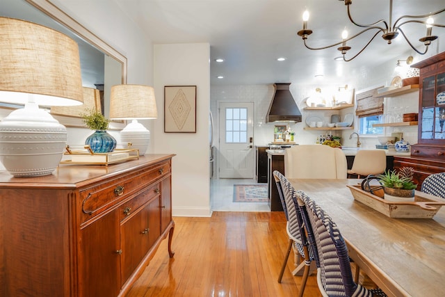 dining space featuring sink, a notable chandelier, and light wood-type flooring