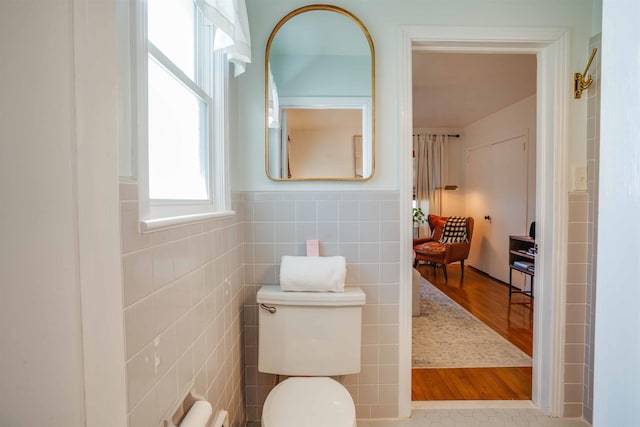 bathroom with toilet, tile walls, and tile patterned floors