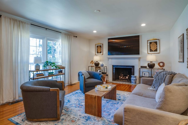 living room featuring a brick fireplace and light hardwood / wood-style flooring