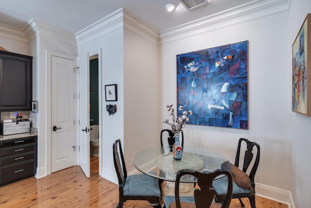 dining area featuring light wood-type flooring and ornamental molding