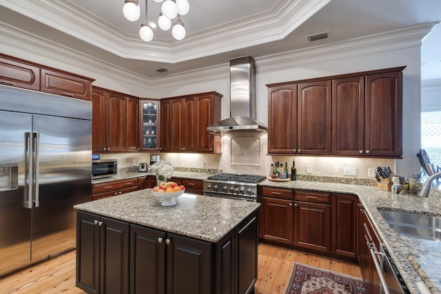 kitchen featuring light hardwood / wood-style flooring, sink, light stone counters, wall chimney range hood, and high quality appliances