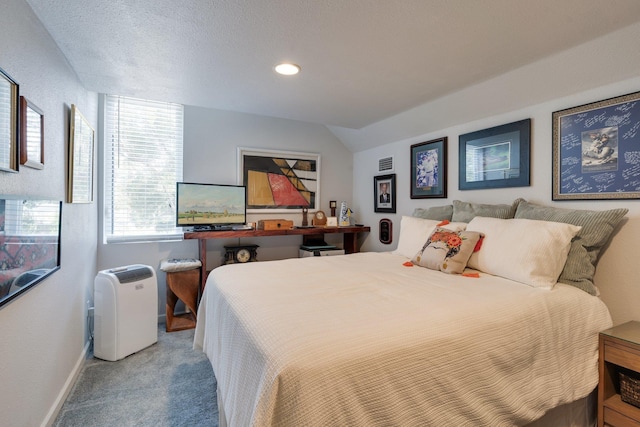 bedroom with carpet floors, vaulted ceiling, and a textured ceiling