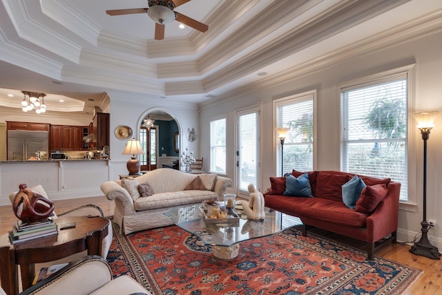 living room with light hardwood / wood-style flooring, crown molding, ceiling fan, and a raised ceiling