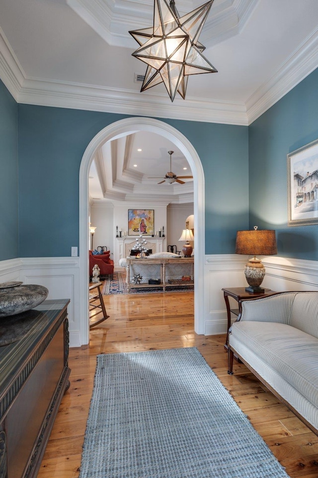 interior space with ceiling fan, light hardwood / wood-style flooring, crown molding, and a raised ceiling