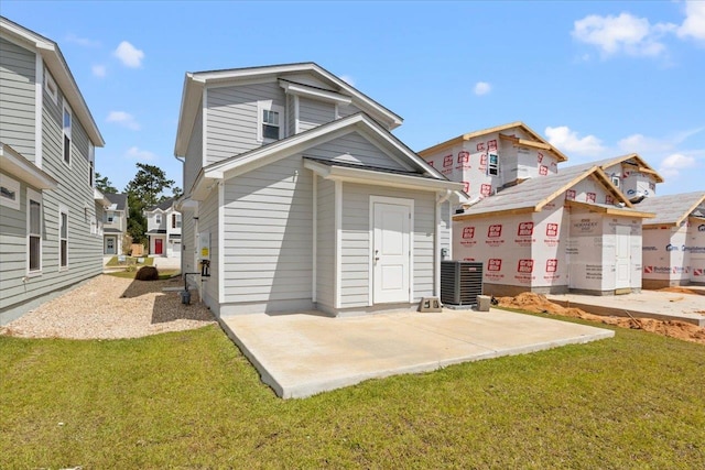 back of property with central air condition unit, a lawn, and a patio area