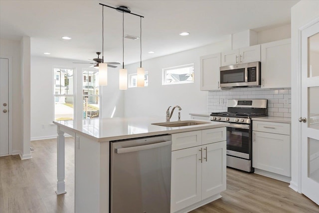 kitchen with white cabinetry, stainless steel appliances, sink, and an island with sink