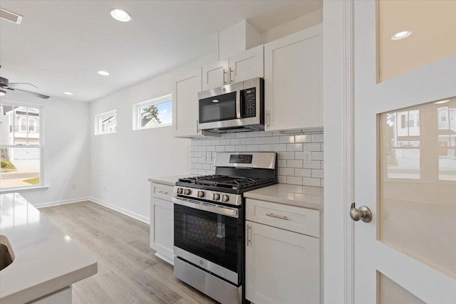 kitchen featuring tasteful backsplash, appliances with stainless steel finishes, white cabinets, ceiling fan, and light hardwood / wood-style flooring