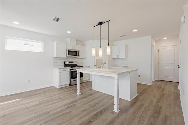 kitchen featuring appliances with stainless steel finishes, decorative light fixtures, light hardwood / wood-style floors, and white cabinets