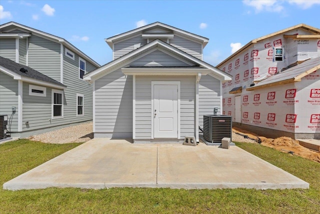 rear view of house with a lawn, central AC unit, and a patio area