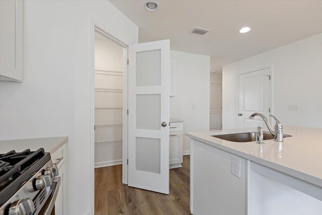 kitchen featuring white cabinetry, stainless steel stove, sink, and light hardwood / wood-style flooring