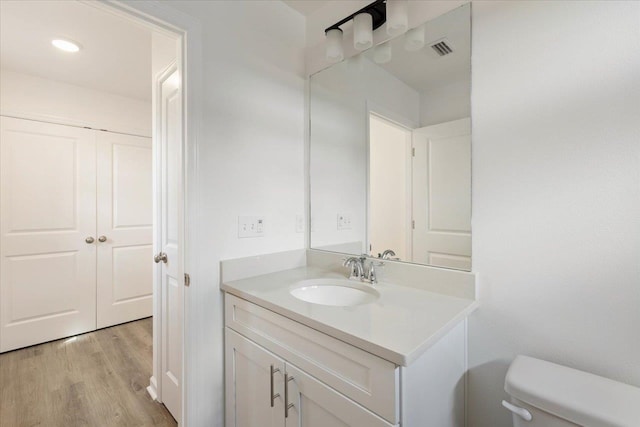 bathroom with toilet, vanity, and hardwood / wood-style floors