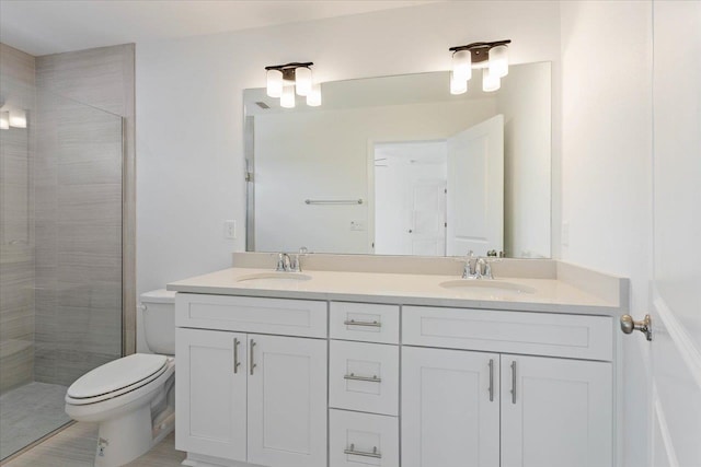 bathroom with a tile shower, vanity, and toilet