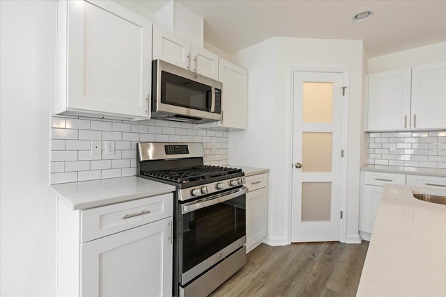 kitchen featuring white cabinetry, decorative backsplash, appliances with stainless steel finishes, and light hardwood / wood-style floors