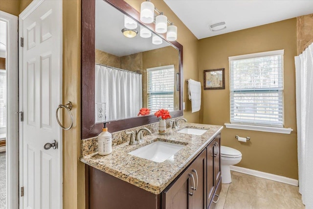 bathroom featuring a healthy amount of sunlight, toilet, tile patterned flooring, and vanity